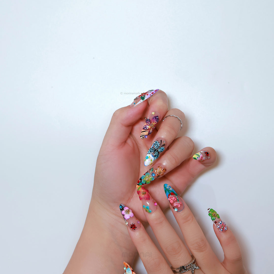 Enchanted Garden press-on nails on hand, with colorful 3D butterfly and flower botanical nail art.
