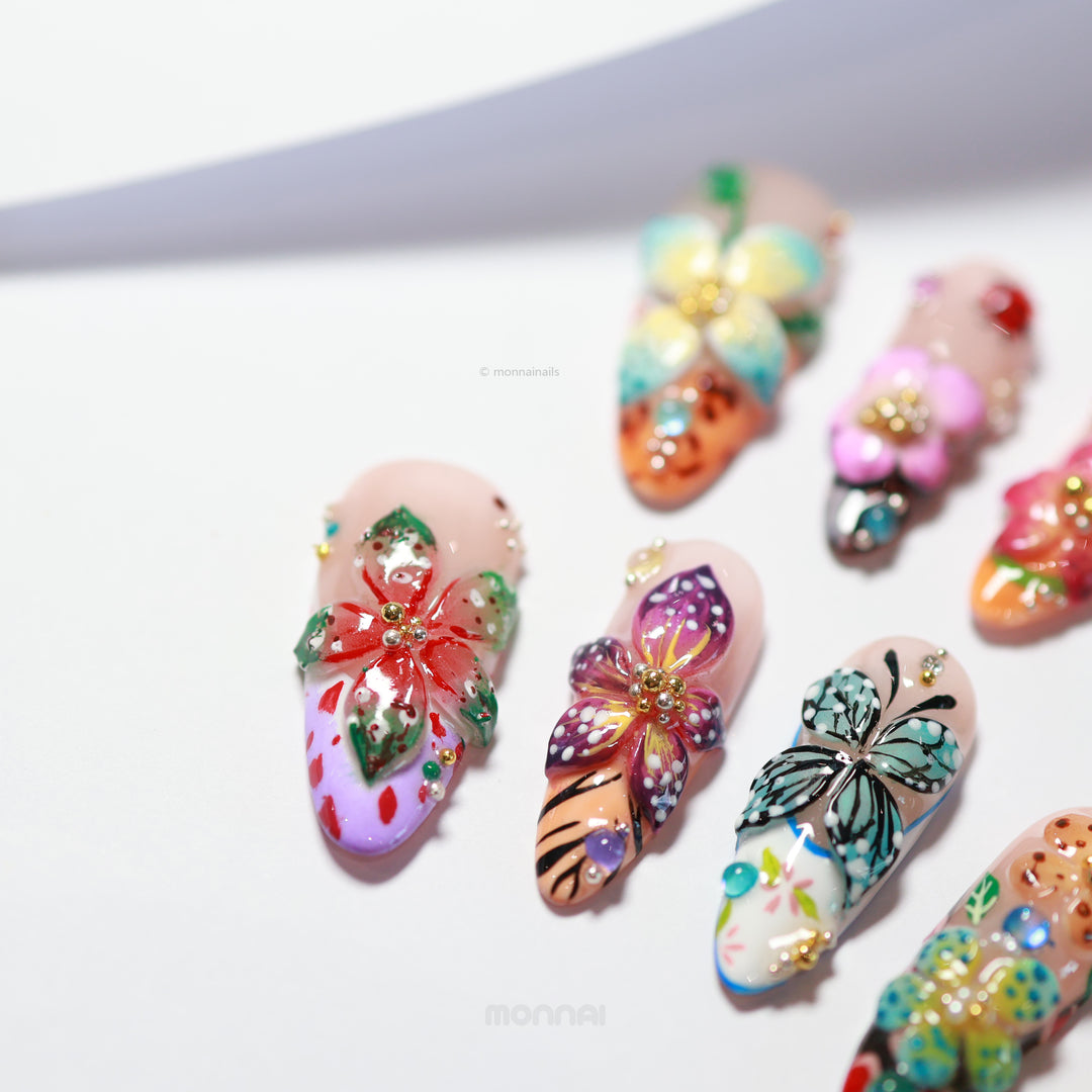 Enchanted Garden press-on nails laid out with vivid 3D hand-painted butterflies and flowers in a colorful botanical design