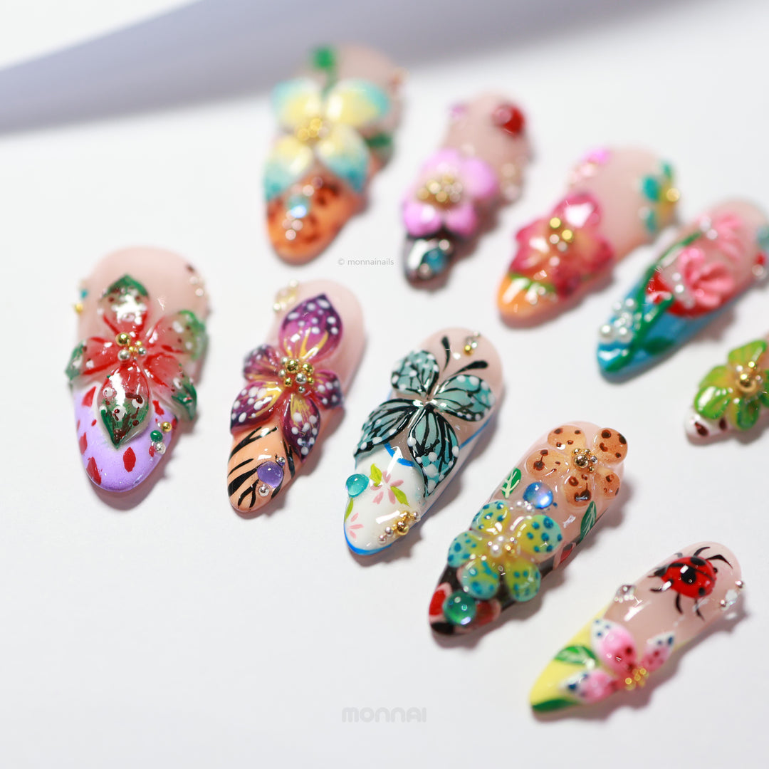 Enchanted Garden press-on nails laid out with 3D hand-painted butterflies and flowers in vivid multicolor designs