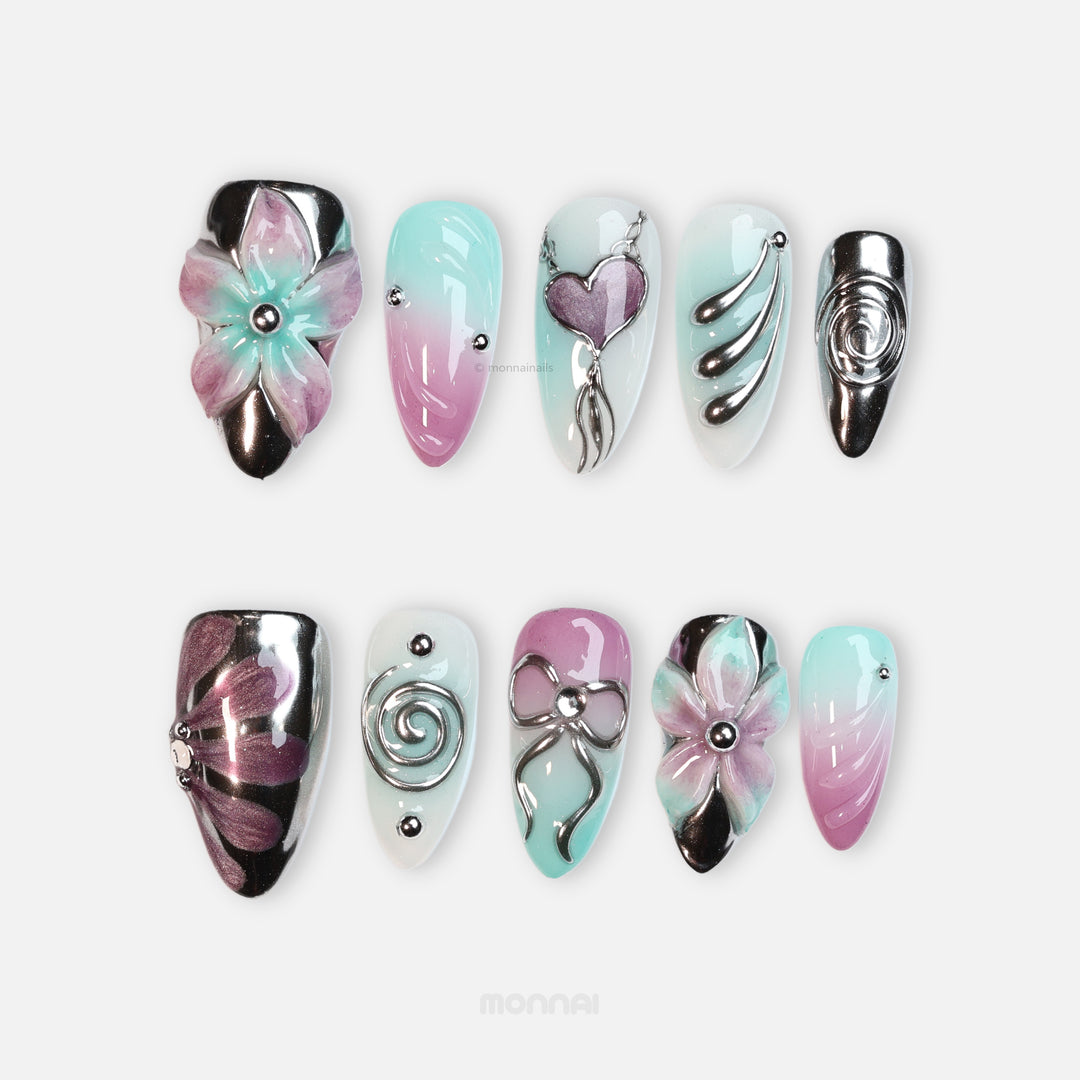 Enchanted Love press-on nails with pastel pink and mint florals, chrome hearts, and sleek glossy details in a laid-out set