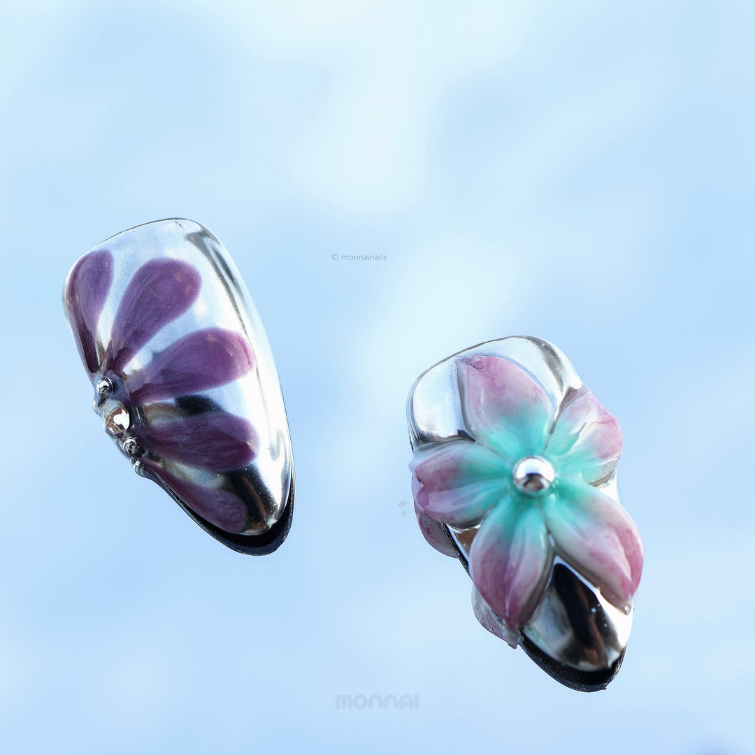 Enchanted Love press-on nails shown in close-up with glossy chrome, purple petals, and a pastel floral accent.