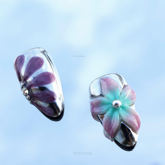 Enchanted Love press-on nails shown in close-up with glossy chrome, purple petals, and a pastel floral accent.