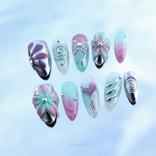 Enchanted Love press-on nails laid out in pastel pink and mint with chrome floral and heart motifs