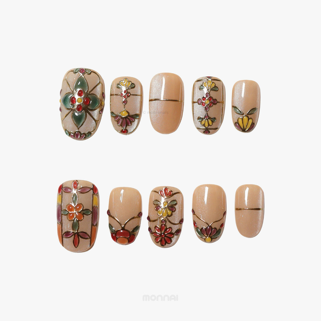 Eternal Grace press-on nails laid out in a vintage ornate stained-glass floral design with champagne-gold shimmer