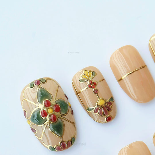 Eternal Grace press-on nails in close-up, showing champagne-gold vintage stained-glass florals and metallic linework.