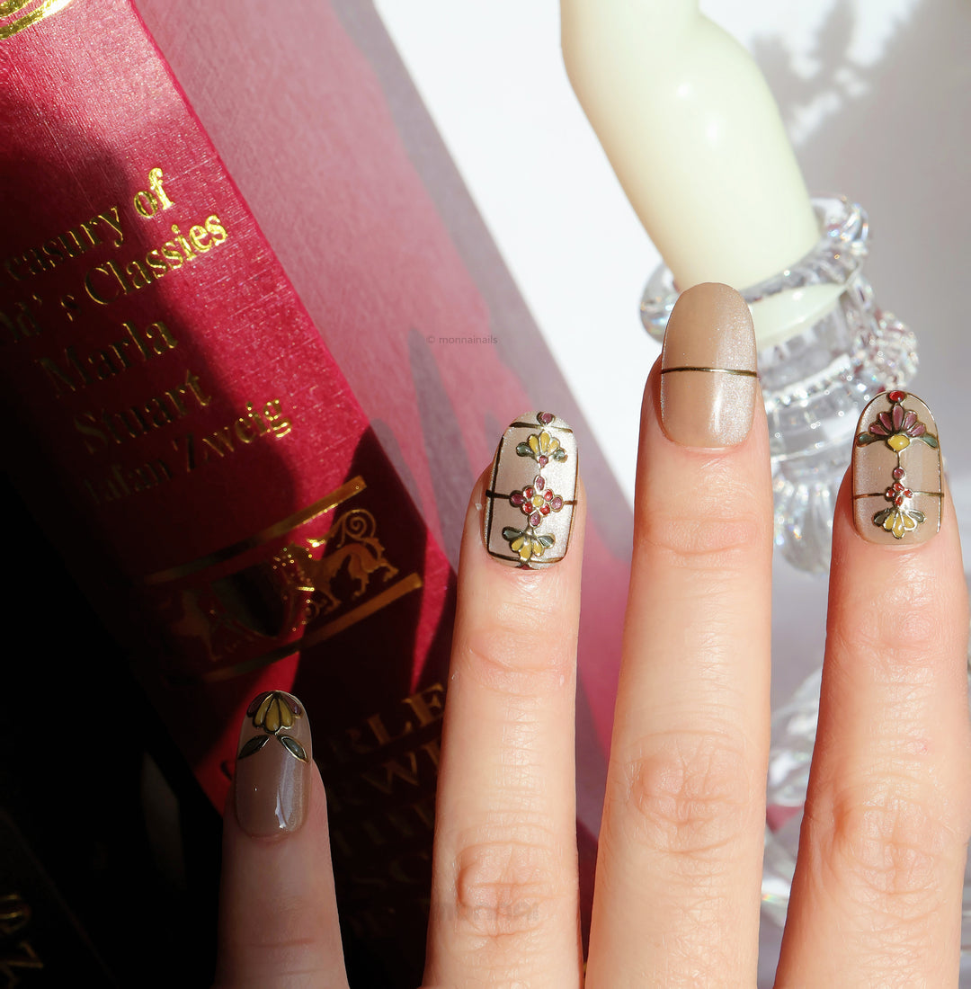 Eternal Grace press-on nails worn on hand, champagne-gold shimmer with ornate stained-glass floral details and metallic linework.