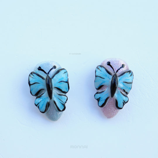 Ethereal Reverie press-on nails with blue butterfly details and glittery cat-eye bases shown in close-up