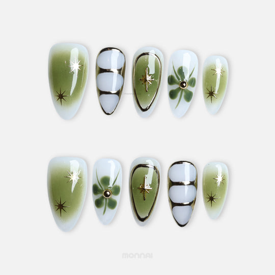Evergreen press-on nails laid out with green gradients, clover-like florals, fine linework and gold star accents