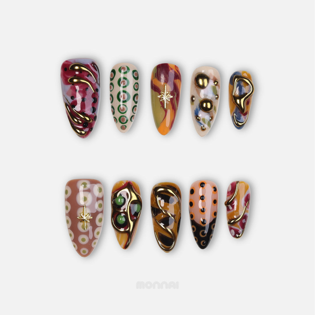 Everything Everywhere in Gold press-on nails laid out with mismatched abstract swirls, retro dots, and gold chrome accents