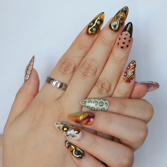 Everything Everywhere in Gold press-on nails on hands, with gold chrome accents, abstract swirls, and retro dots in an artsy, bold style.