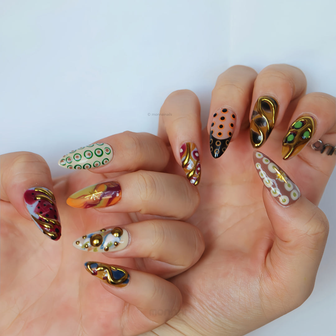 Everything Everywhere in Gold press-on nails worn on hands, showcasing mismatched abstract swirls, retro dots, and gold chrome accents.