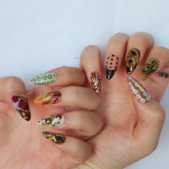 Everything Everywhere in Gold press-on nails worn on hands, showcasing mismatched abstract swirls, retro dots, and gold chrome accents.