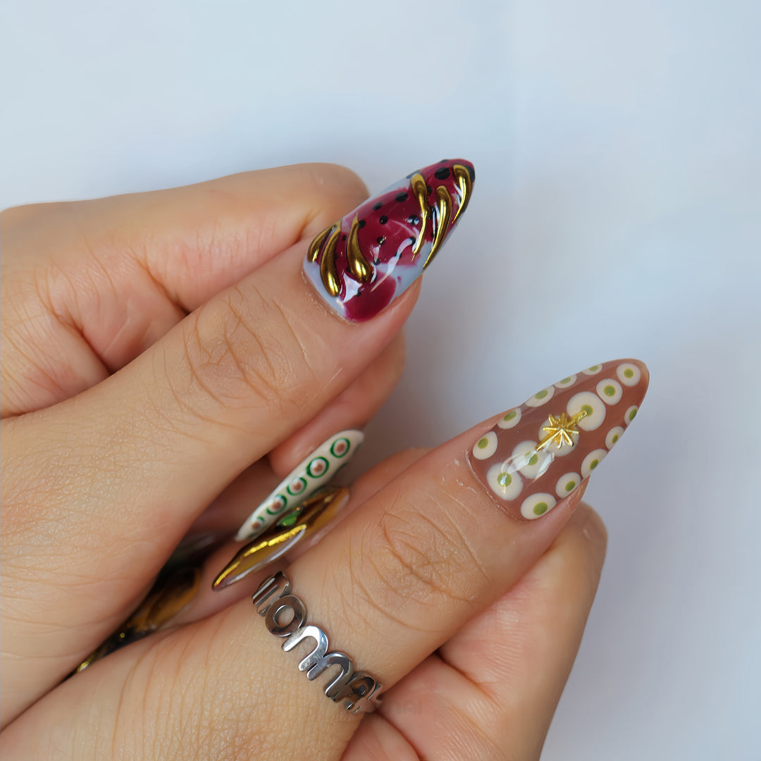 Everything Everywhere in Gold press-on nails worn on hand, showing mismatched abstract swirls, retro dots and gold chrome accents.