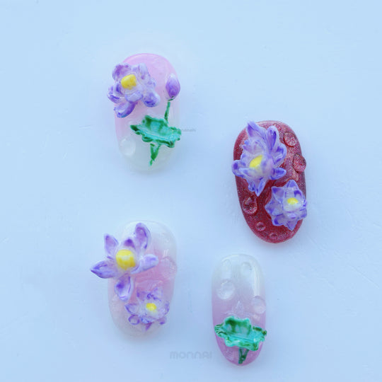 Fairy Pond press-on nails laid out with raised purple lotus flowers, glossy water drops, and sheer pastel bases.