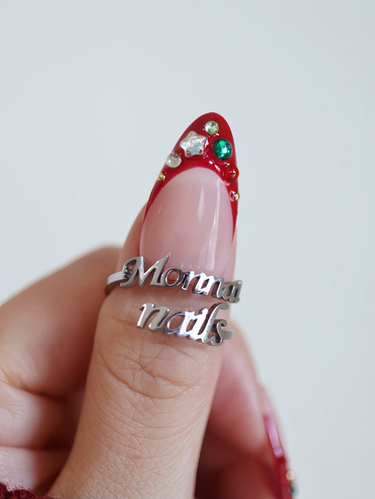 Festive Jewels press-on nails on hand with red French tip, crystal stars, colorful jewels, and silver ring
