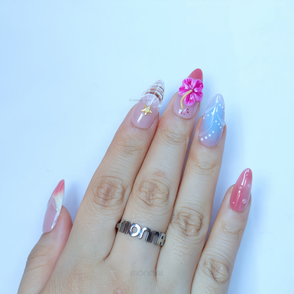 Finding Summer press-on nails worn on hand with sheer nude, pastel blue and coral accents, shell texture, hibiscus and starfish details