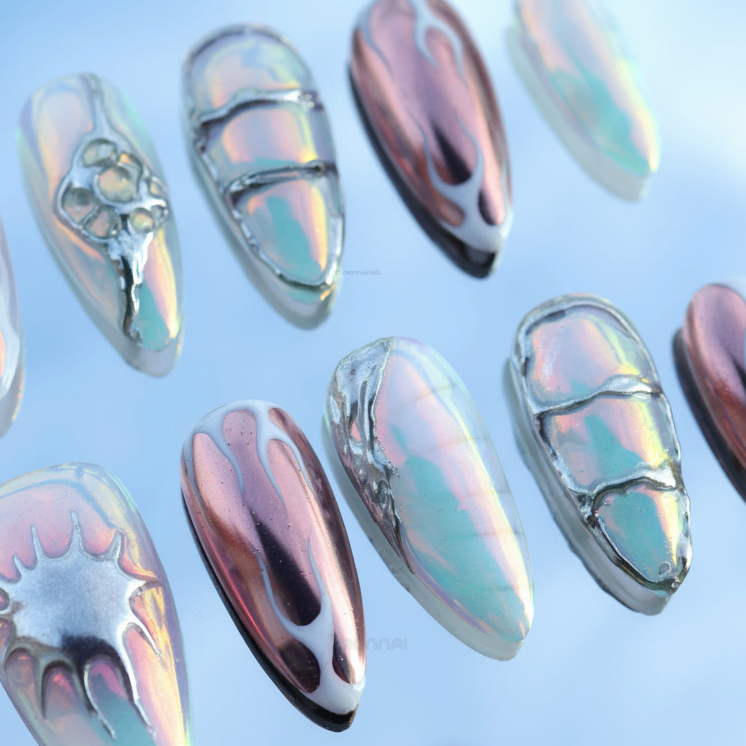 Flame Gradient press-on nails laid out with icy blue chrome, holographic sheen, and sculpted flame-inspired detailing