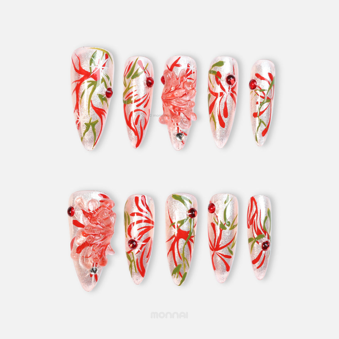 Flame Rebirth press-on nails laid out, silver cat-eye shine with red floral strokes, green accents, and crystal flower details.