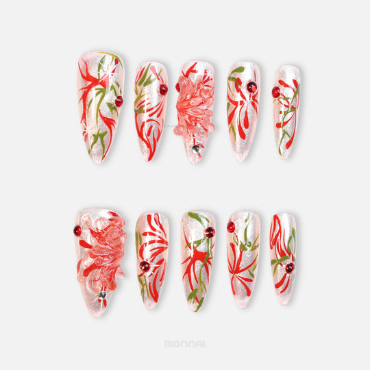 Flame Rebirth press-on nails laid out, silver cat-eye shine with red floral strokes, green accents, and crystal flower details.