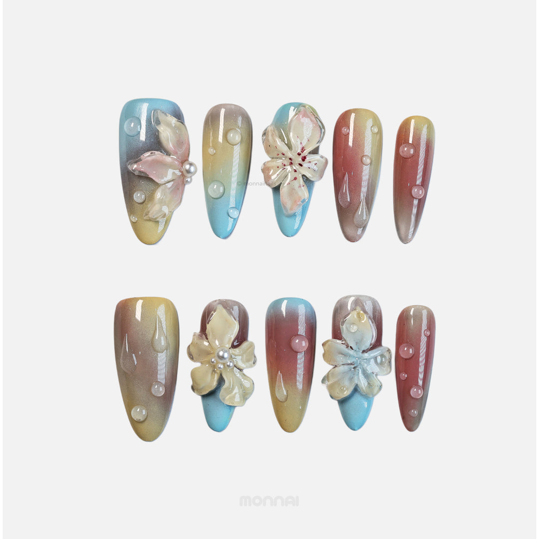 Floral Sunset press-on nails laid out with glossy 3D flowers, bubble droplets, and warm blue-to-rose gradients.