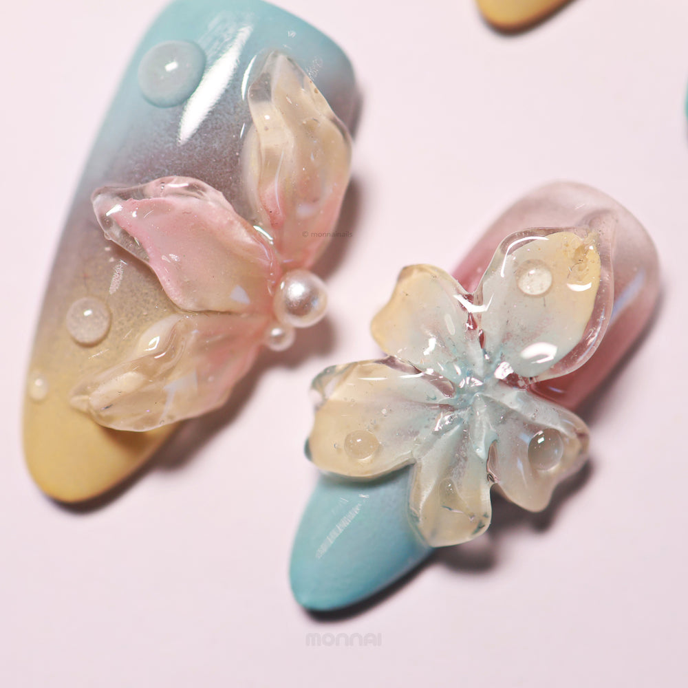 Floral Sunset press-on nails with pastel gradients, sculpted 3D flowers, and glossy bubble droplets in close-up.