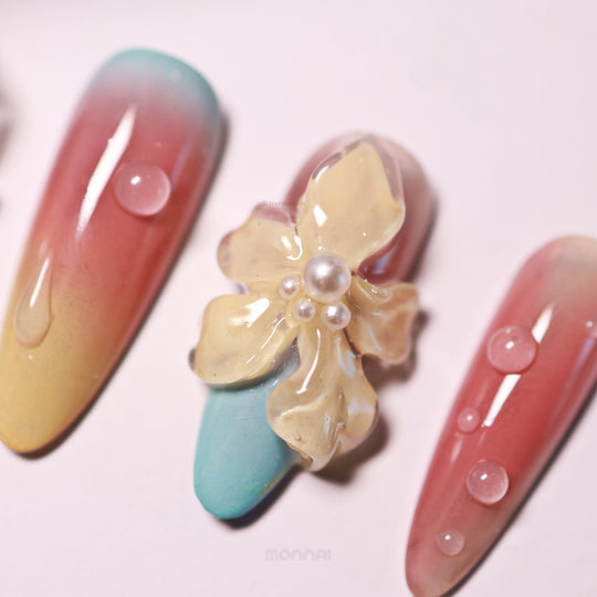 Floral Sunset press-on nails in close-up, with glossy gradient nails and a sculpted 3D flower accented by bubble-like droplets.
