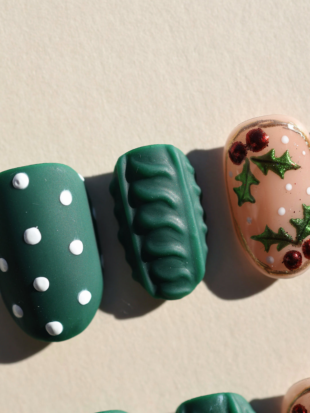 Forest Dots press-on nails laid out: green matte dots, a 3D cable knit nail, and nude holiday accent art.