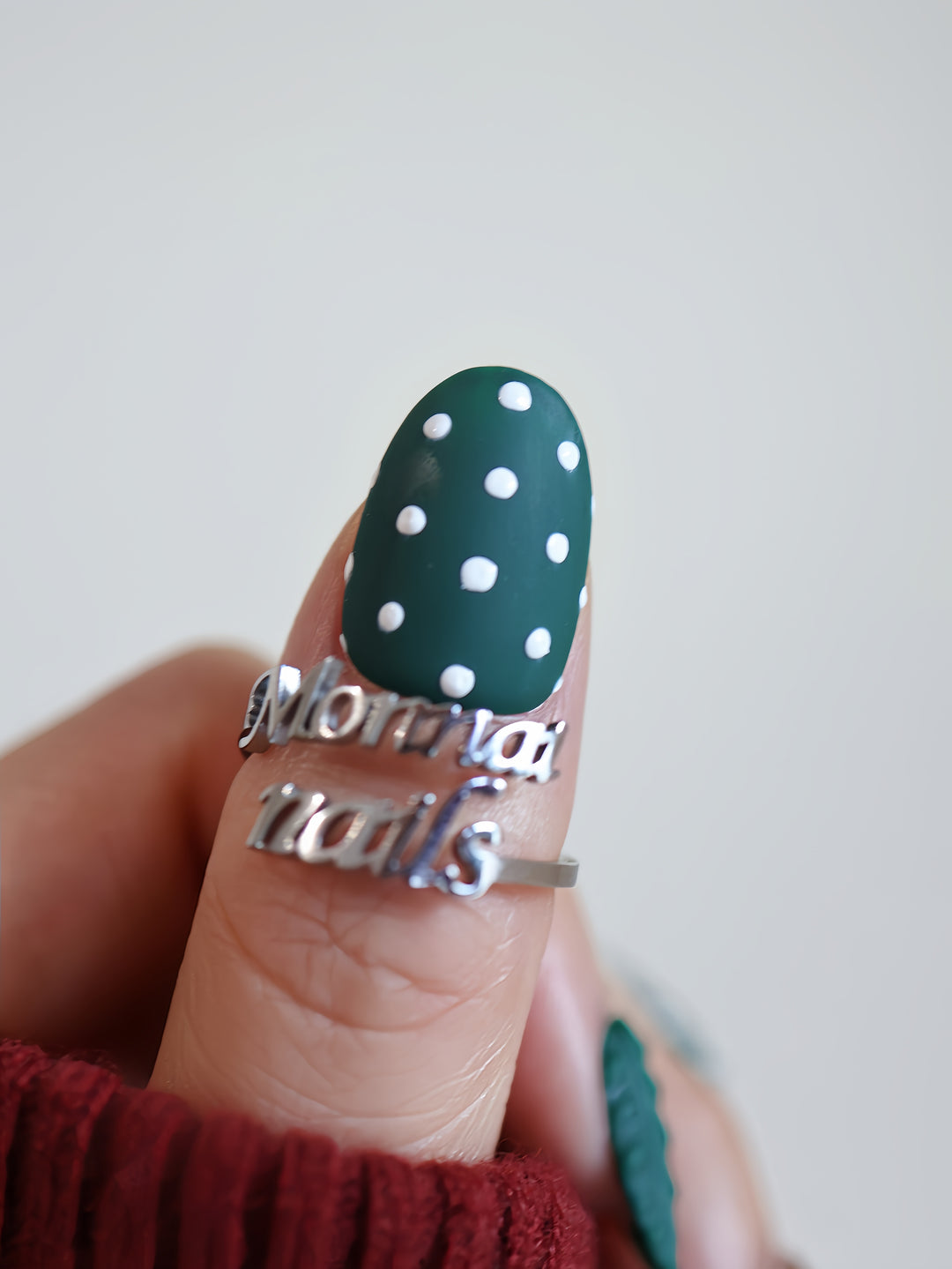 Forest Dots press-on nails on hand, dark green matte oval nail with white polka dots