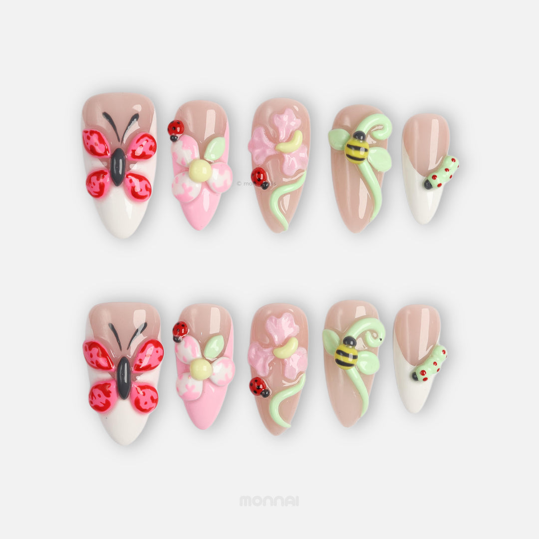 Garden Party press-on nails laid out with soft nude and milky white butterfly, flower, bee and ladybug details.