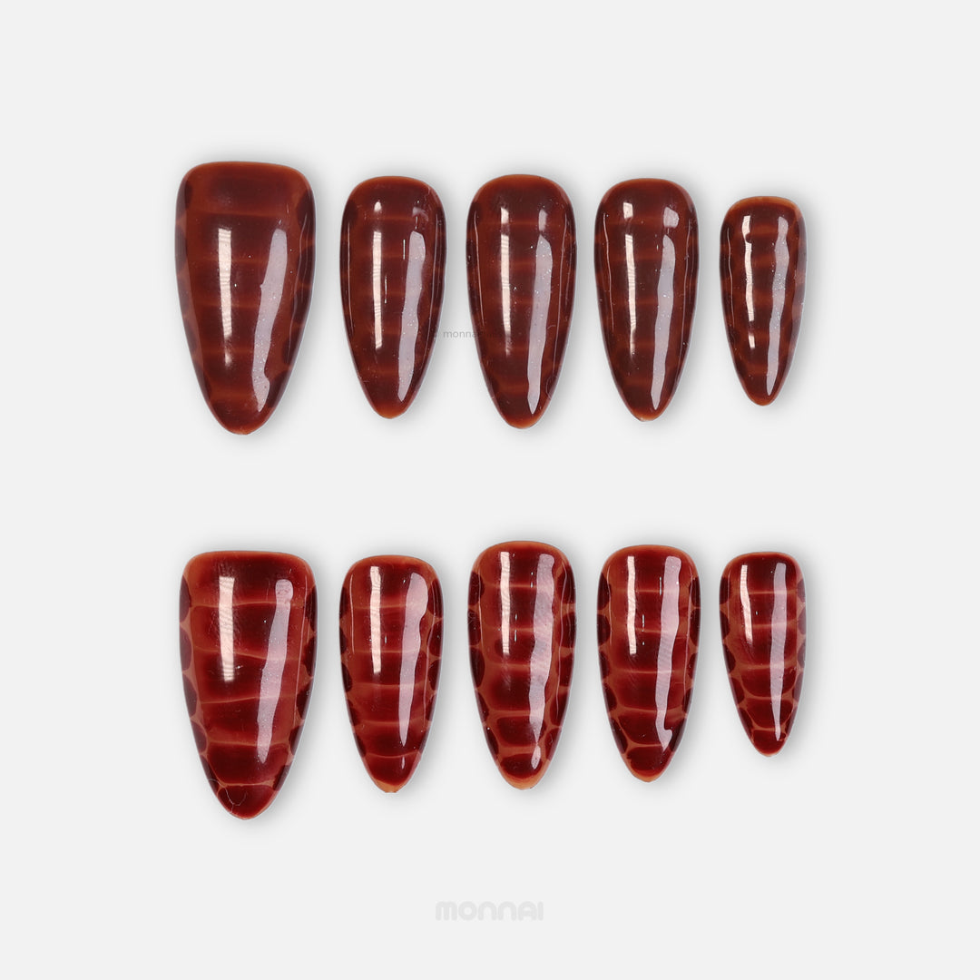 Gator Glaze press-on nails in deep brown with glossy crocodile texture, shown in two laid-out sets.