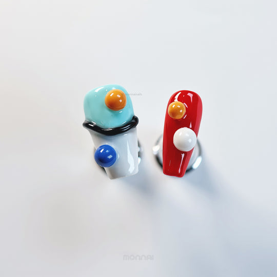 Geo Pop press-on nails in close-up, with glossy red and aqua abstract shapes, orange dots, and a blue accent.
