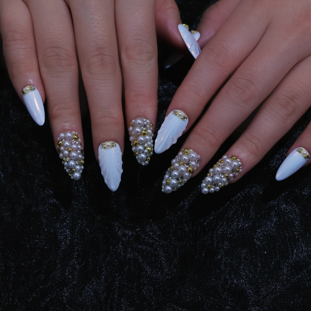 Gilded Pearls press-on nails shown on hands, with white shell textures, clustered pearls, and gold crystal accents.