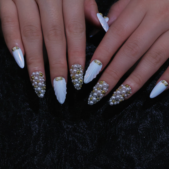 Gilded Pearls press-on nails shown on hands, with white shell textures, clustered pearls, and gold crystal accents.