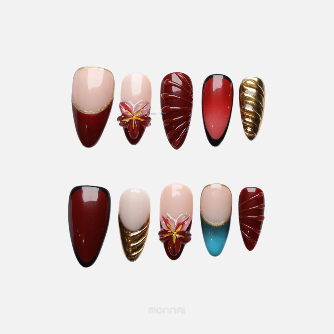 Gilded Rouge press-on nails laid out in wine red, nude and gold with floral gel details