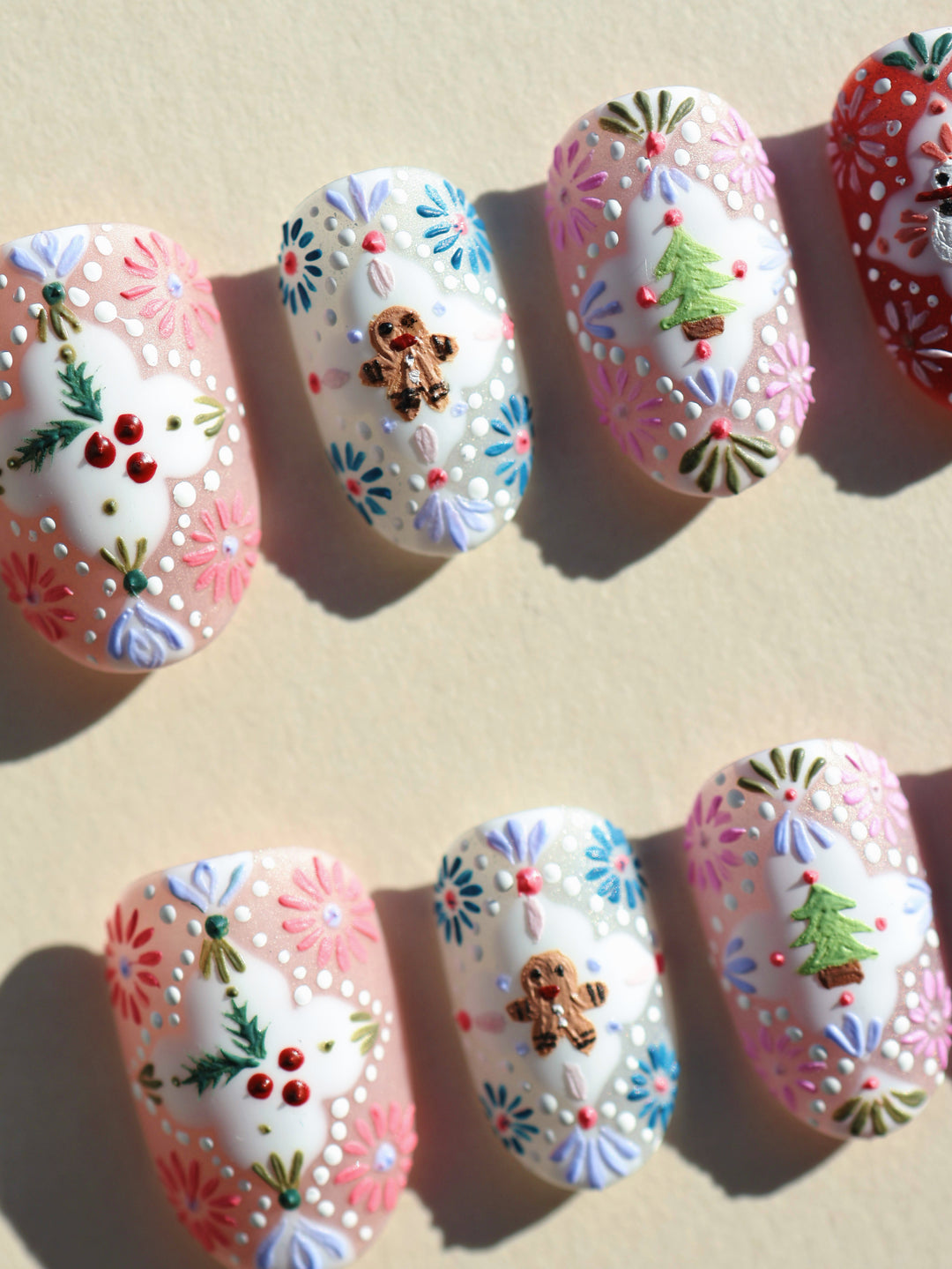 Ginger Cookie Christmas-themed press-on nails laid out with gingerbread, tree and floral embossed details.