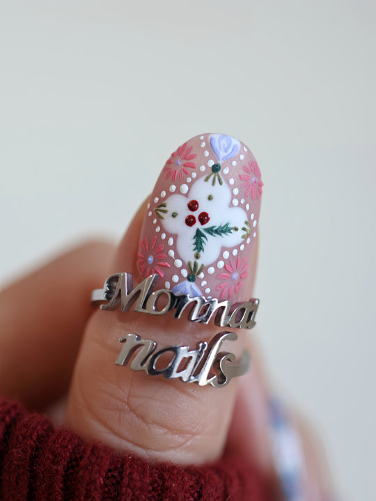 Ginger Cookie Christmas-themed press-on nails close-up on a thumb, with embossed floral dots and a white folk-art center.