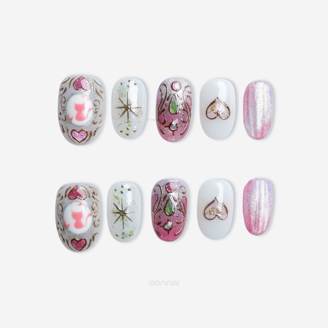 Girl's Cat press-on nails laid out in pink cat eye shimmer with heart details, cat art, and soft silver accents