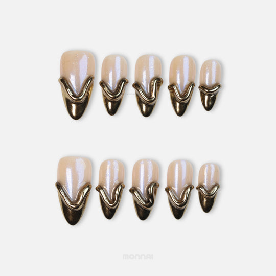 Golden Drip press-on nails laid out, showing nude nails with glossy gold French tips and raised sculpted lines.