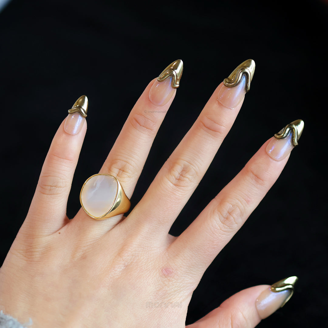 Golden Drip press-on nails on hand, nude base with gold French tips and raised sculpted lines