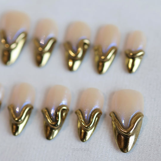 Golden Drip press-on nails in close-up, nude base with gold French tips and sculpted raised lines.