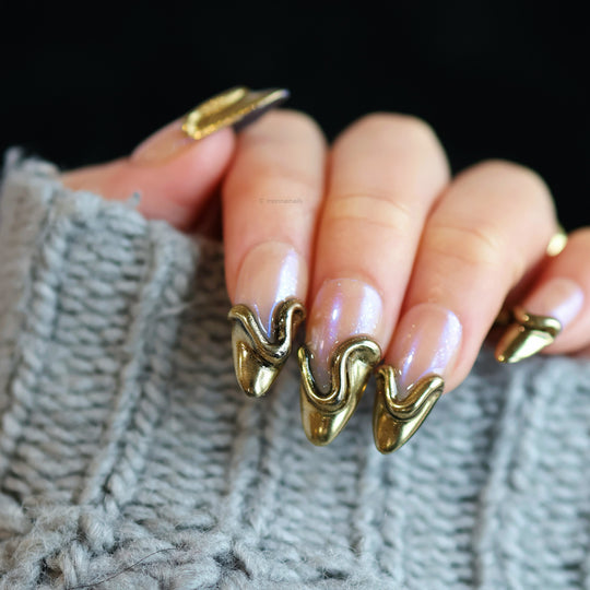 Golden Drip press-on nails with nude base, gold French tips, and sculpted raised lines on hand