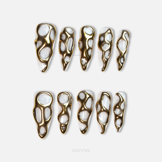 Golden Flow press-on nails with liquid-metal gold shapes on milky white, shown laid out in two rows
