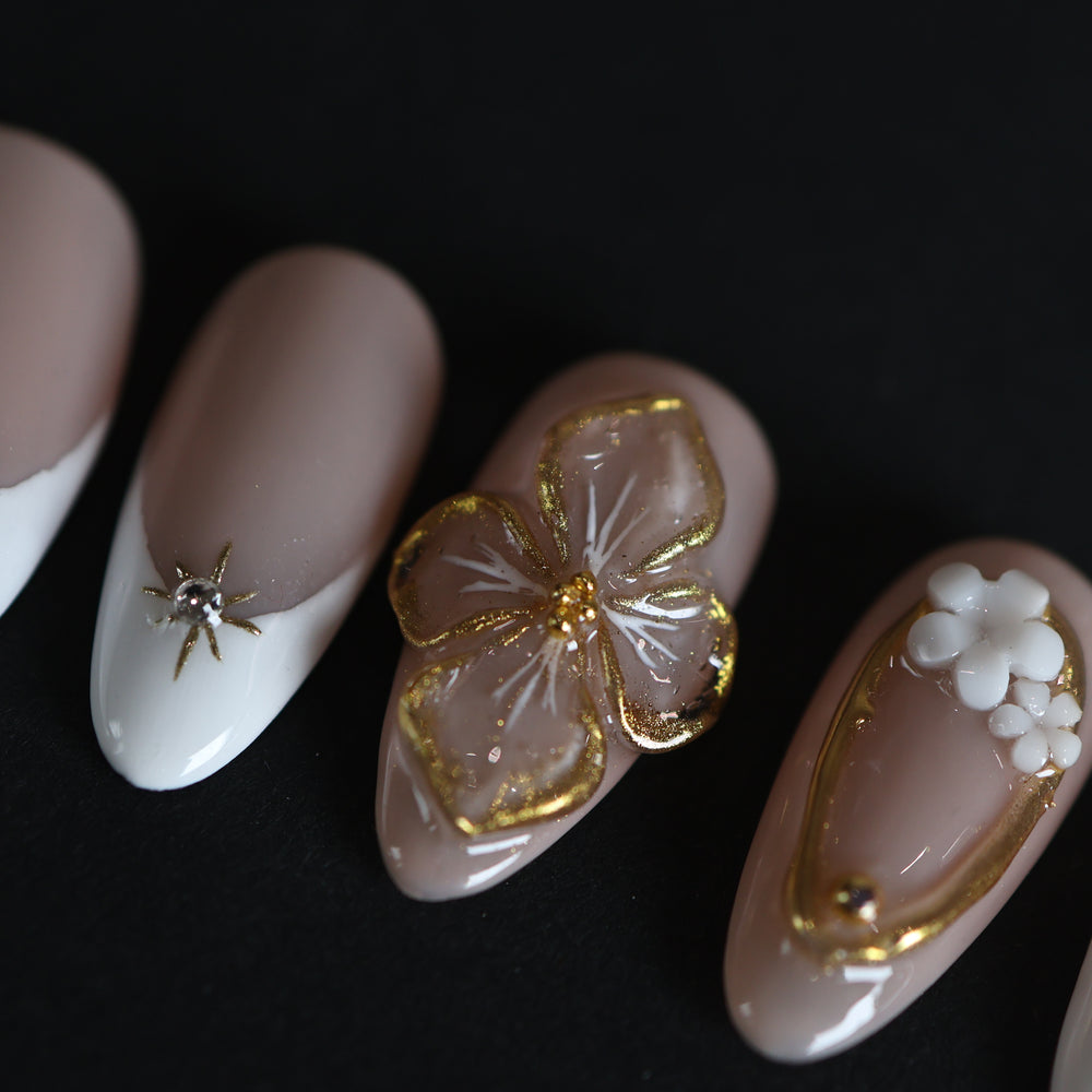 Golden Hour bridal press-on nails with nude and white French tips, gold 3D floral accents, and rhinestone star charm
