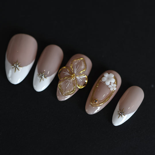 Golden Hour bridal press-on nails in nude and white French tips with gold 3D floral accents and rhinestone stars