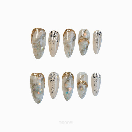 Golden Marble press-on nails laid out with creamy beige smoky stone texture, gold accents, and glitter flakes