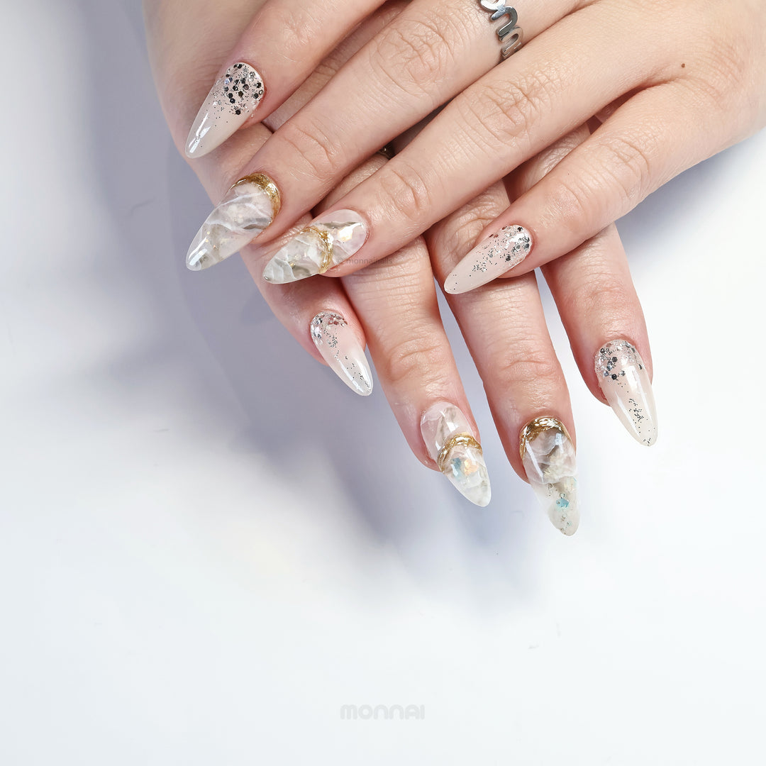 Golden Marble press-on nails worn on hands, with creamy beige marble, iridescent flakes, and metallic gold accents.