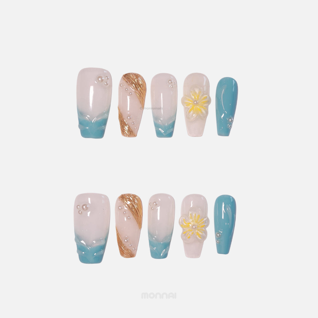 Golden Shore press-on nails laid out with milky white, teal tips, gold accents and 3D floral pearls in tropical modernism.