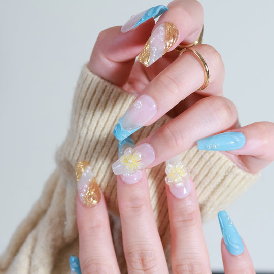 Golden Shore press-on nails worn on hand, tropical modernism with milky white, teal tips, gold accents and floral pearls.