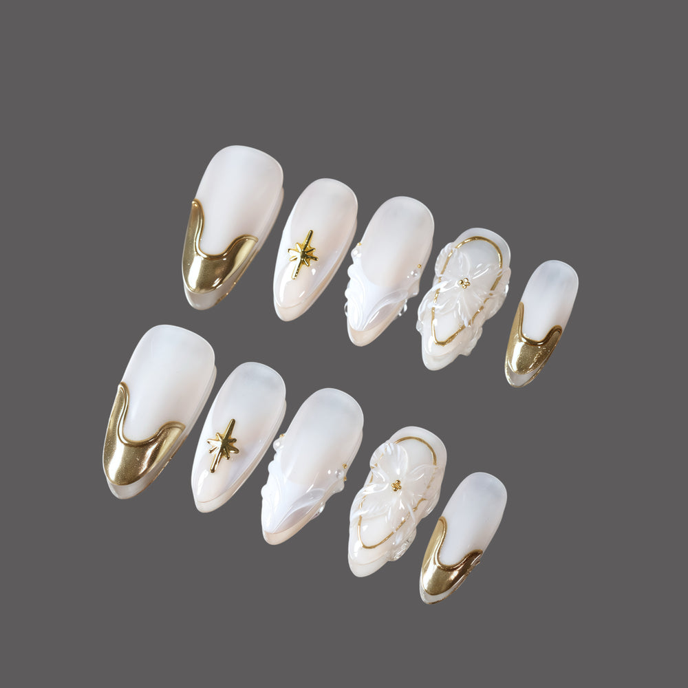Golden Veil press-on nails set with milky white base, gold chrome tips, starburst, florals, and pearl accents