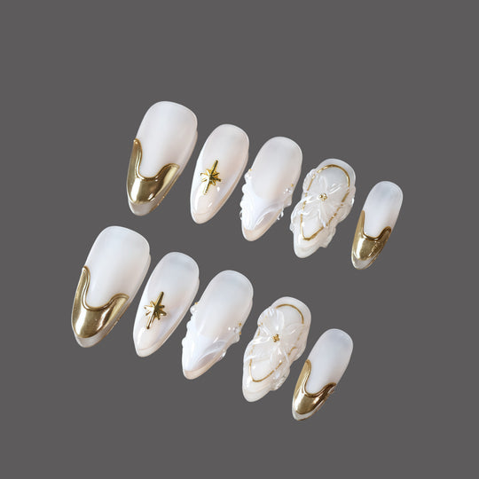 Golden Veil press-on nails set with milky white base, gold chrome tips, starburst, florals, and pearl accents